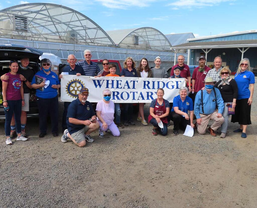 The Wheat Ridge Rotary club volunteers stand outside of a greenhouse